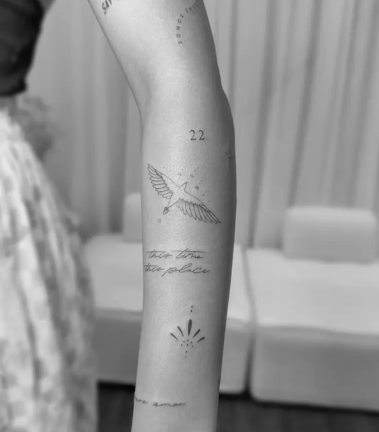 Fine line bird in flight tattoo with script text and numerical elements by Chelsea.Q